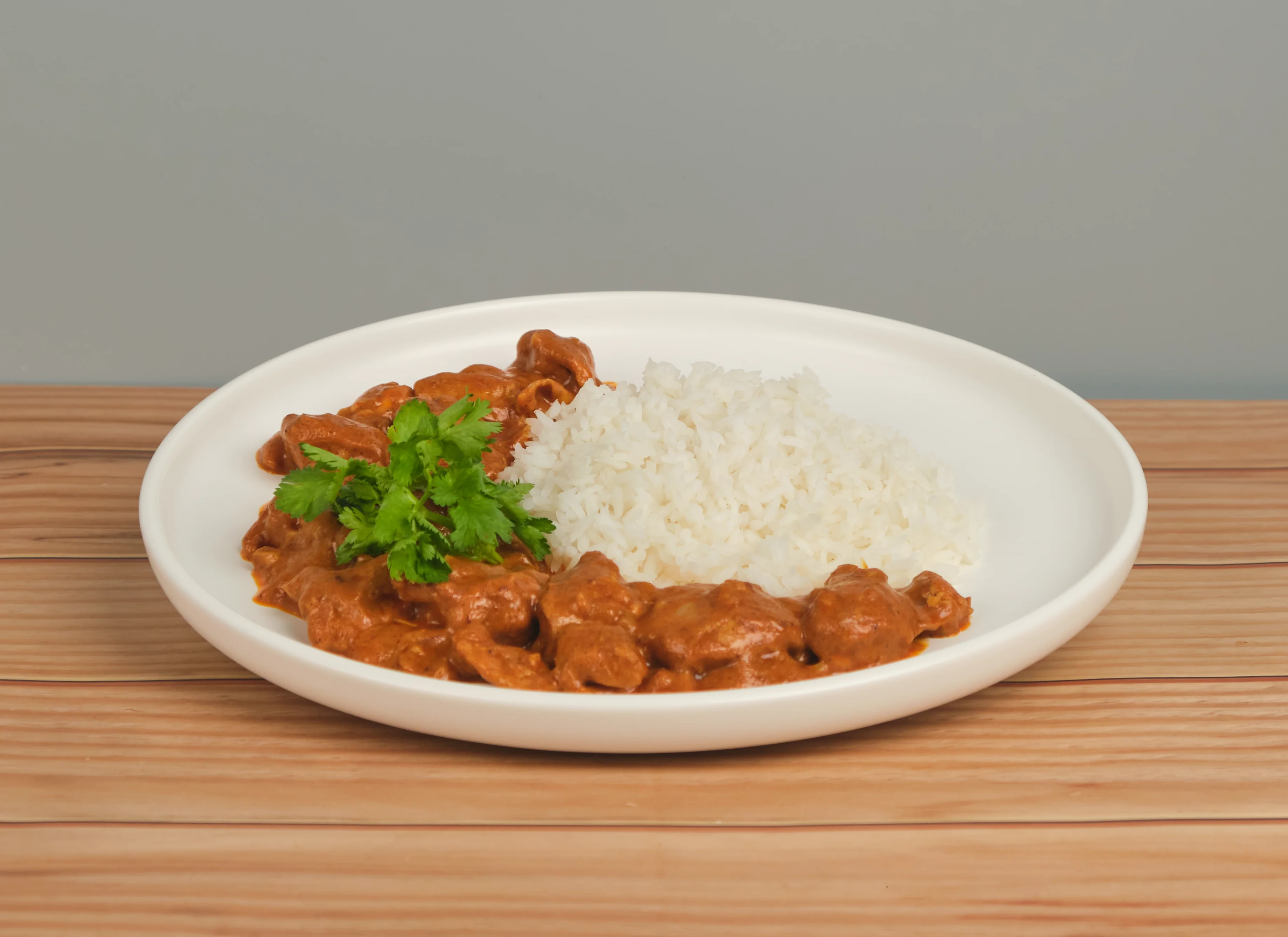 Buttered chicken plated for service, rich orange sauce over rice